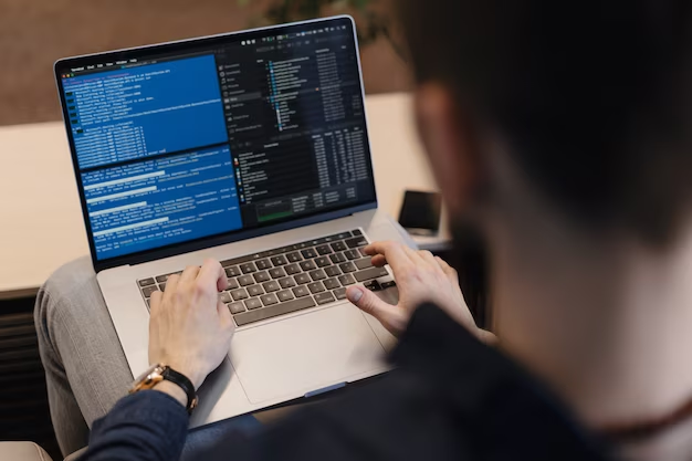 A man writes code on a laptop